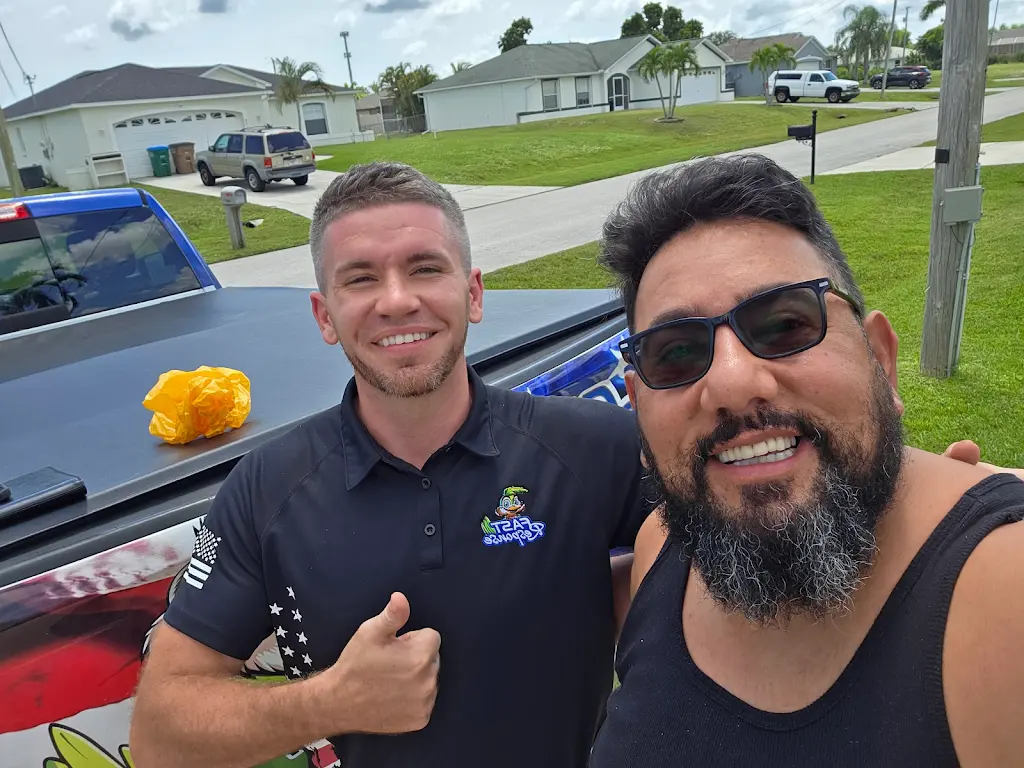 Fast Response technician giving a thumbs up next to a Carrier condenser after a completed service call in Cape Coral