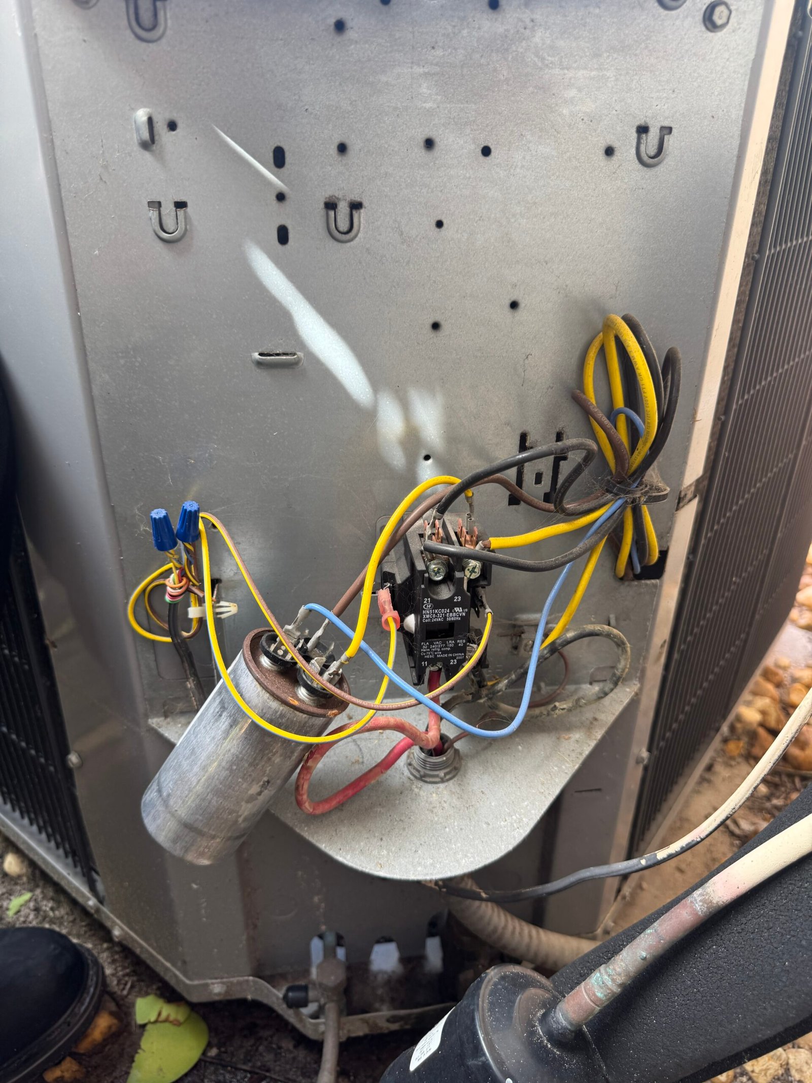 Close-up of the internal wiring, capacitor, and contactor of an outdoor AC unit during routine maintenance by technician Ryan in Estero, Florida.